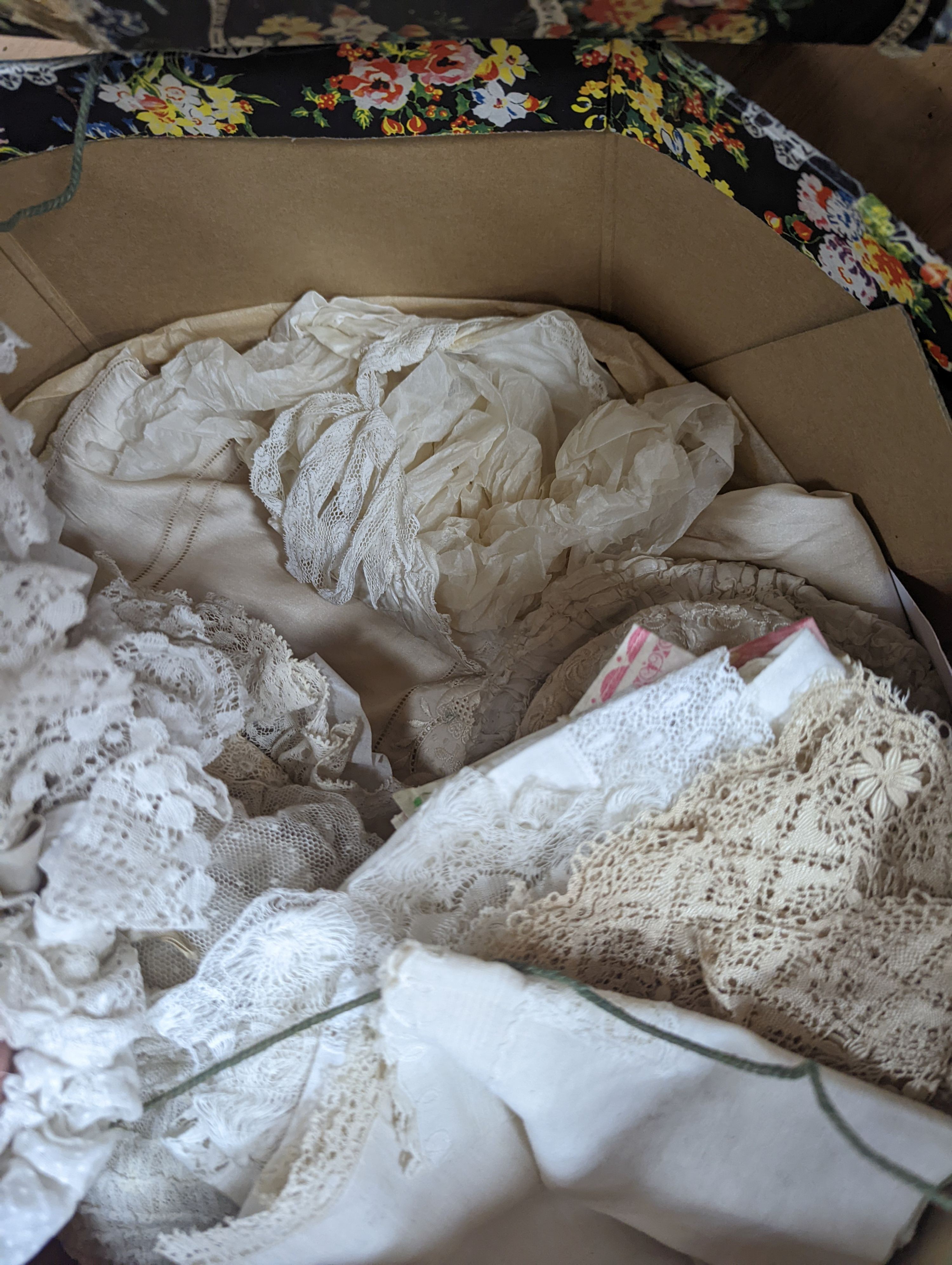 A collection of lady’s and baby's lace bonnets, various hankies and a cream silk embroidered skirt.